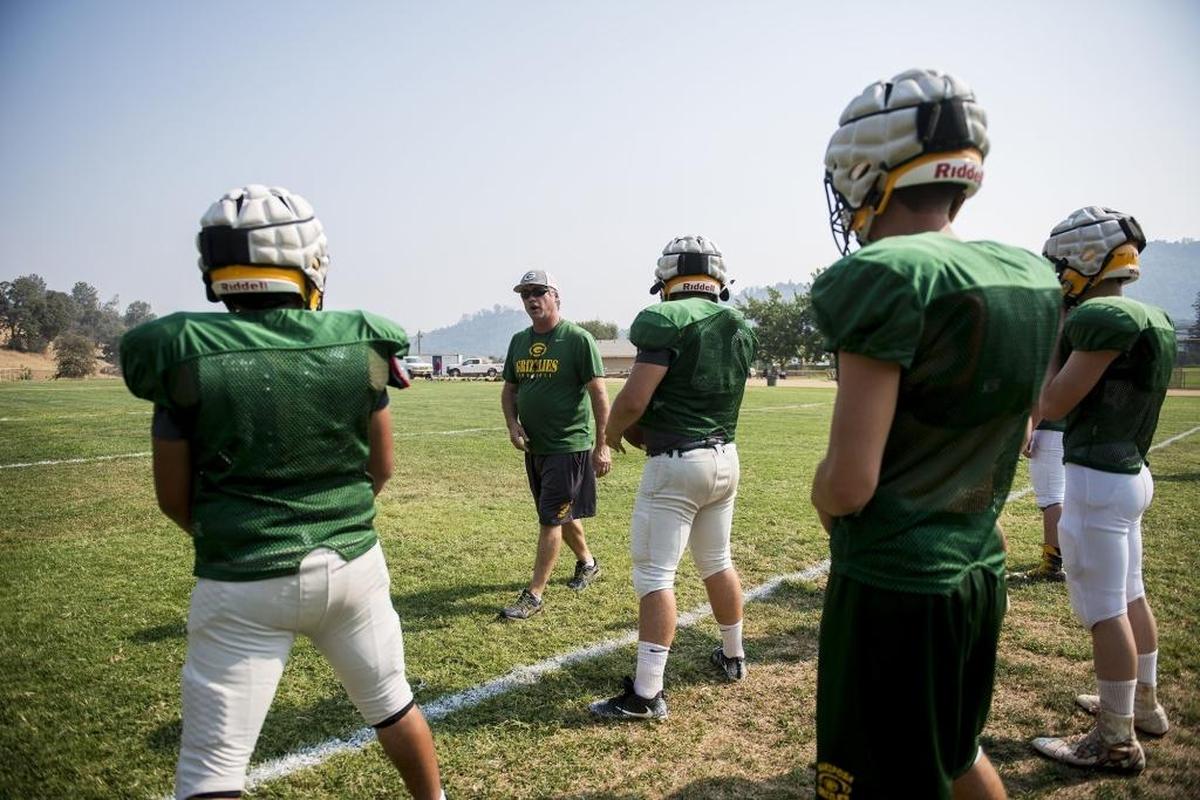 Head coach Robert Stitt, second from left, works with players during football practice at Mariposa High School in Mariposa, Calif., on Tuesday, Aug. 7, 2018.