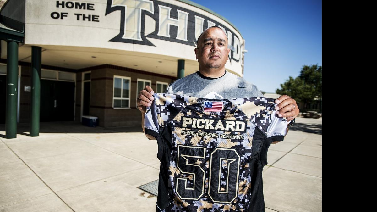 Buhach Colony High School football coach Kevin Navarra, above, holds a jersey honoring former Thunder football player Joshua Pickard on Thursday.  The jersey will be worn by a deserving Thunder player for a week during practice. Below, the jersey also will carry the school’s mascot and motto, THOR: toughness, heart, ownership, and respect.