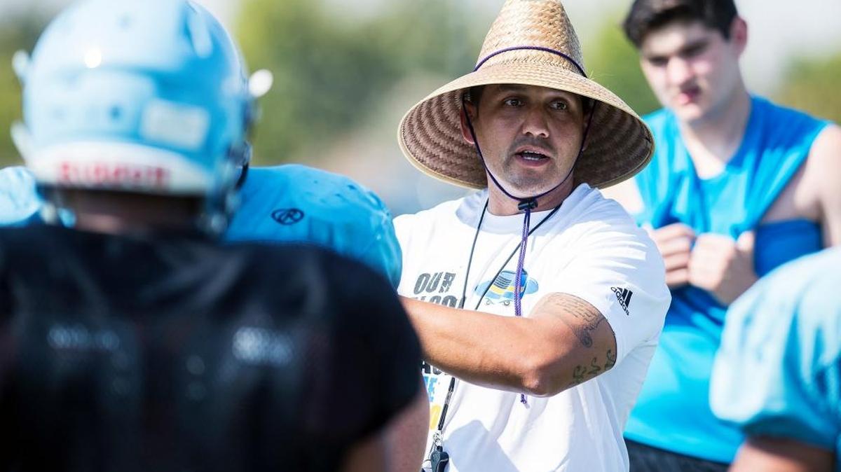 Varsity football coach Frank Solis, left, speaks to his players during practice at El Capitan High School in Merced, Calif., on Wednesday, Aug. 16, 2017.