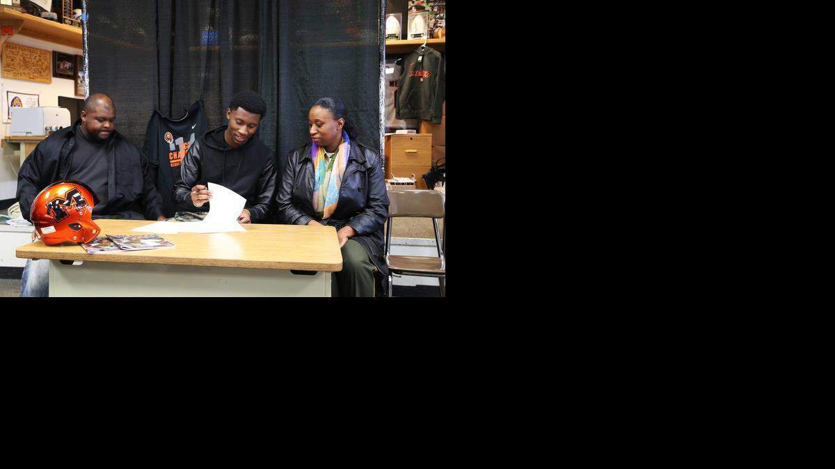 
Merced High School senior Tyrone Williams looks over his national letter of intent as his father Tyrone and mother Monique look on. Williams accepted a scholarship to play football at Azusa Pacific University.
