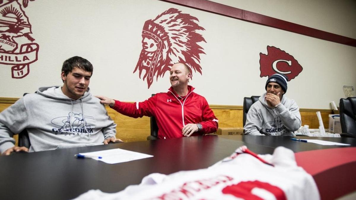 Chowchilla High School head football coach Alex Pittz, center, jokes around with senior football players Gary Niewkoop, left, and Alex Gutierrez, right, as the two sign their letters of intent to attend Concordia University, Nebraska in the School Board Room at Chowchilla High School in Chowchilla, Calif., Wednesday, Feb. 3, 2016.