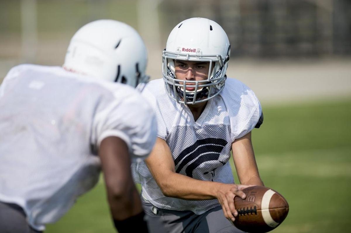 Stone Ridge Christian quarterback Ethan Moradzedeh hands the ball off during football practice in Atwater, Calif., on Friday, Aug. 3, 2018.