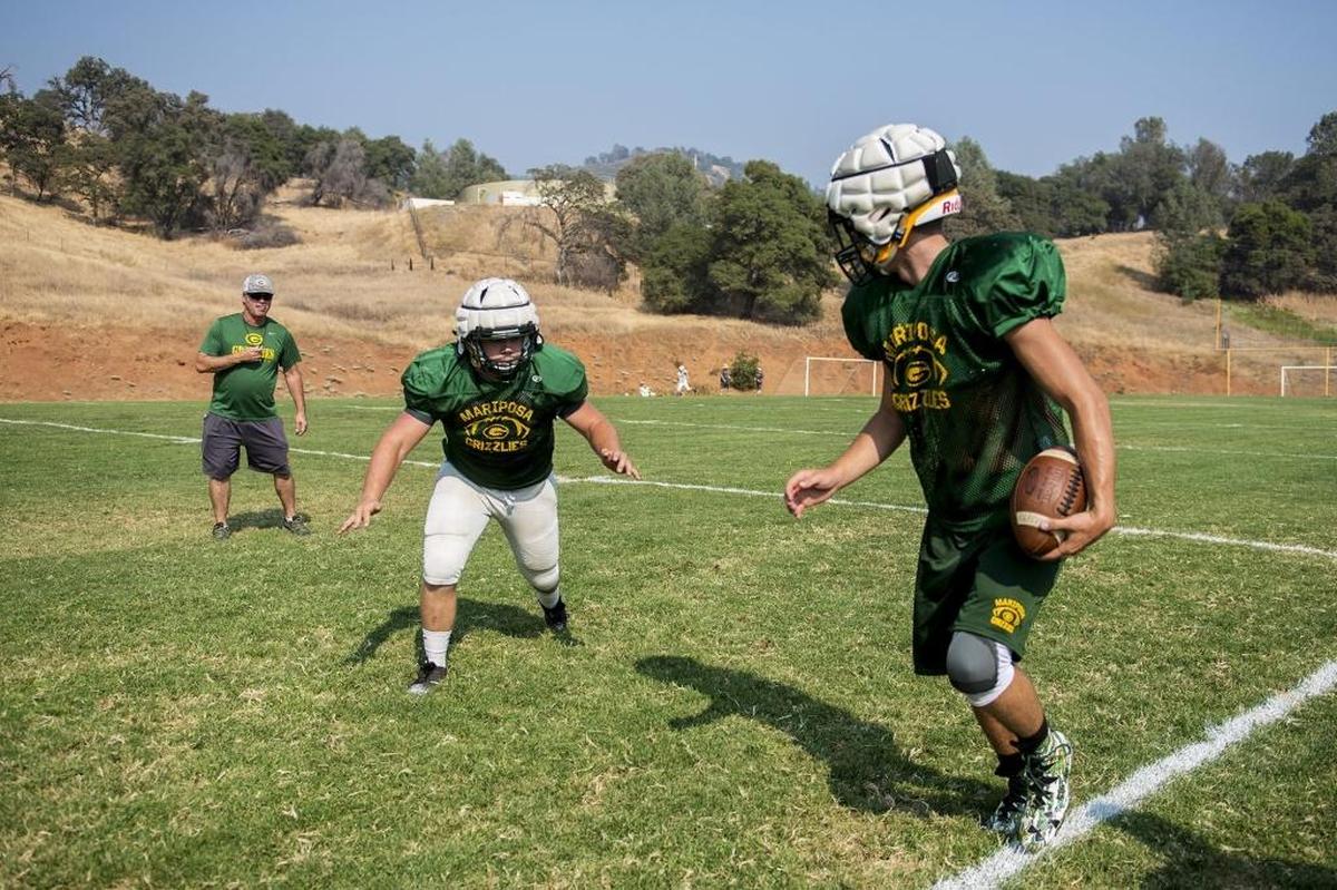 Mariposa players Ryan Leonard, center, prepares to hit J.C. Davis, right, during football practice at Mariposa High School in Mariposa, Calif., on Tuesday, Aug. 7, 2018.