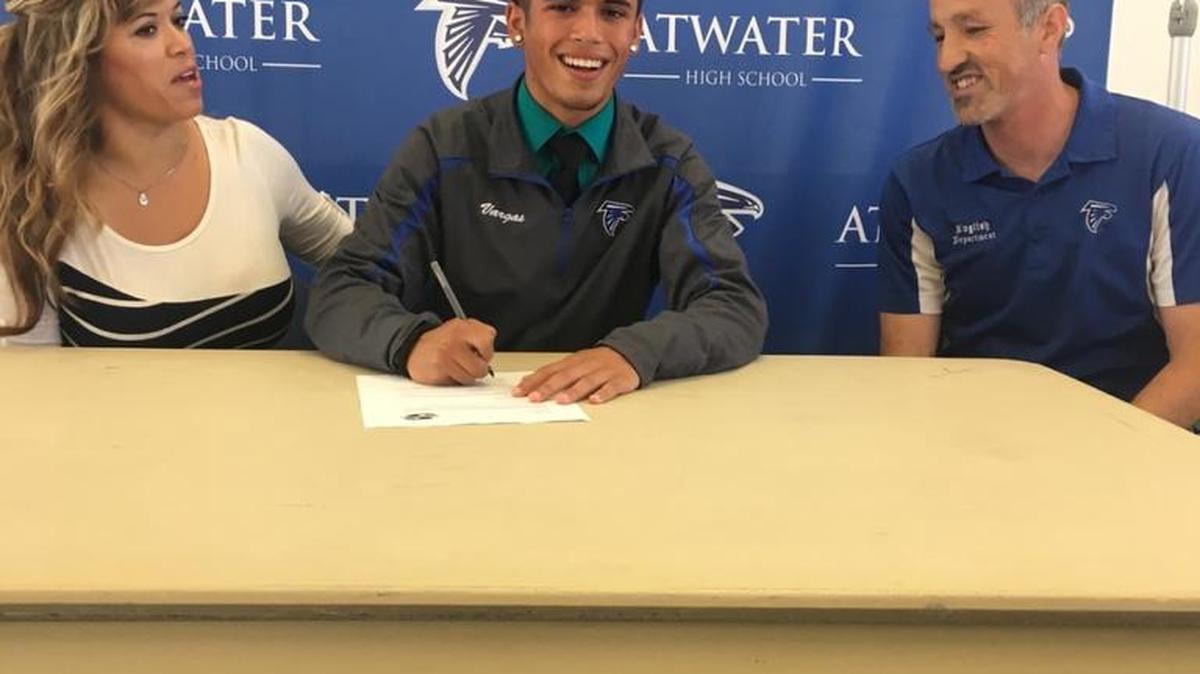 Atwater High senior Alex Vargas signs his national letter of intent to compete in cross country and track & field at Stanislaus State as his mother, Letty Vargas, and Atwater coach Ken Rhoades look on during a ceremony at Atwater High on Wednesday.