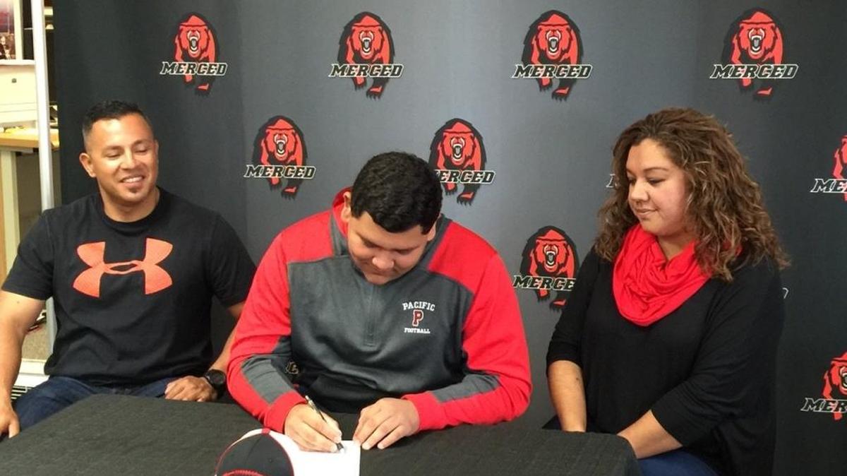 Merced High senior Manuel Ramirez signs his national letter of intent to play football at Pacific University in Oregon on Wednesday morning at Merced High as parents Manuel and Aracely look on.