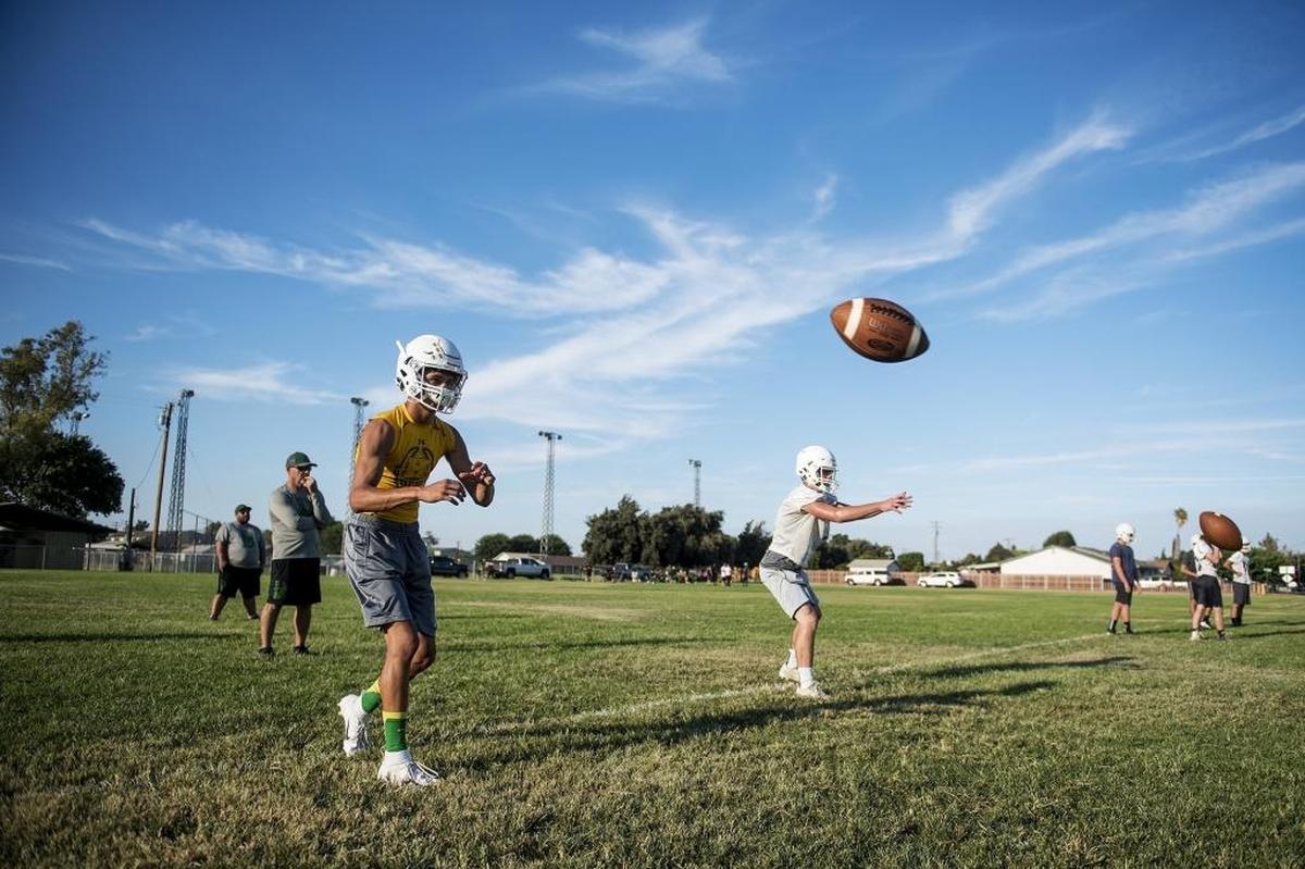 Quarterbacks Treven Crowley, left, and Ryan Teixeira, right, take the snap during football practice at Hilmar High School in Hilmar, Calif., on Wednesday, July 25, 2018.