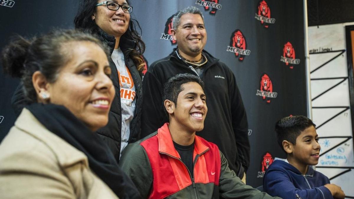 Merced High School graduate Andres Hernandez, center, signed a letter of intent with Cardinal Stritch on Thursday with his mother, Carmela Figueroa, left, brother Alexis Hernandez, right, and Bears coaches Kateri Yaley-Garcia, rear left, and Joel Garcia looking on.