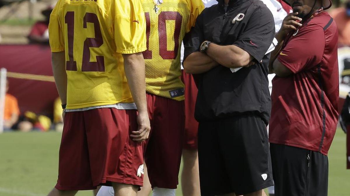 Washington Redskins quarterback coach Matt LaFleur, right, talks with quarterbacks Robert Griffin III, center, and Kirk Cousins (12) on the field as they begin their training camp at the NFL football teams new practice facility in Richmond, Va. Thursday, July 25, 2013.