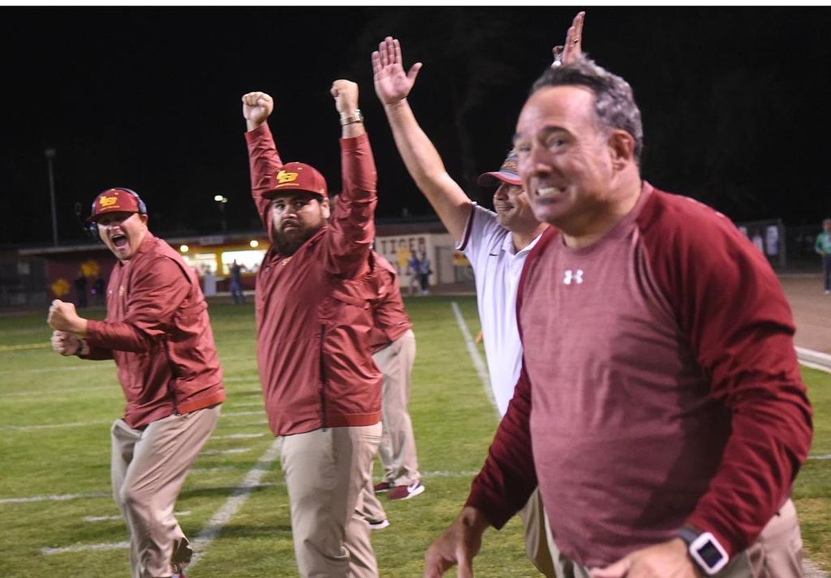Los Banos High School head coach, Dustin Caropreso, left, and fellow assistant coaches celebrate following a win against Orestimba High Fri., Nov. 2, 2018 at Loftin Stadium in Los Banos.