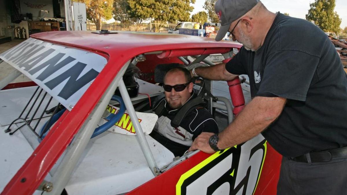 
Shane Hausmann straps into his hobby stock with the help of his dad Mike, right. The Hausmann’s won last Sunday after a long hiatus for family time. 
