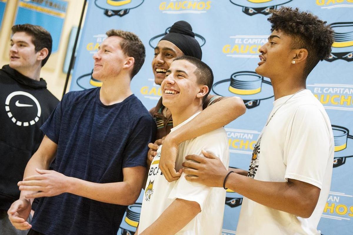 El Capitan senior Angel Serena, second from left, laughs while posing for photos with friends and teammates during a ceremony at El Capitan High School in Merced, Calif., on Friday, April 27, 2018. Serena signed his letter of intent to attend and play basketball for the University of California, Merced.