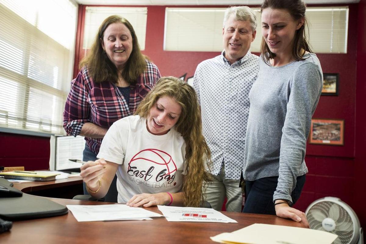 Golden Valley senior Delia Moore, front, signs her letter of intent to play basketball for California State University, East Bay while joined by mother Patti, left, father Brian, center, and sister Valerie, right, at Golden Valley High School in Merced, Calif., on Friday, April 13, 2018.