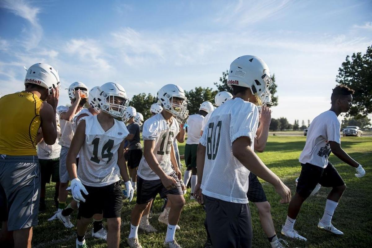 Football players take a water break during practice at Hilmar High School in Hilmar, Calif., on Wednesday, July 25, 2018.