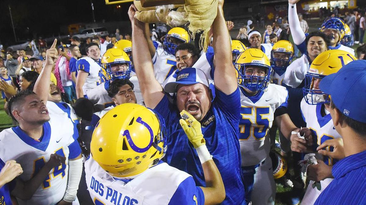 Dos Palos players and coaches celebrate and hold high the Cotton Bale trophy Friday night, Aug. 23, 2019 at Loftin Stadium in Los Banos as Dos Palos was the winner of the Westside War beteween Dos Palos High School and Los Banos High School. Final score was 40-35.